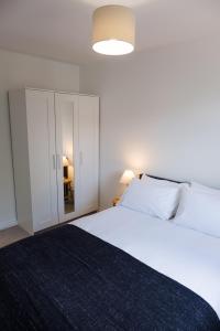 a bedroom with a large white bed and a cabinet at Douglas Apartment in Alexandria