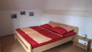ホーエン・ノイエンドルフにあるFerienwohnungのベッドルーム1室(木製ベッド1台、赤いシーツ付)