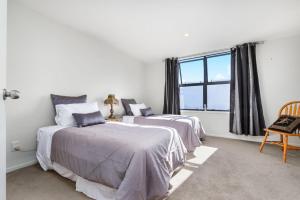 two beds in a white room with a window at Wendy‘s in Auckland