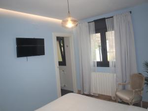 a bedroom with a bed and a chair and a television at Los Patios de Santander in Santander