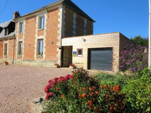 a building with a garage and flowers in front of it at Chambres d'hôtes La Mare aux Saules in Sausseuzemare-en-Caux