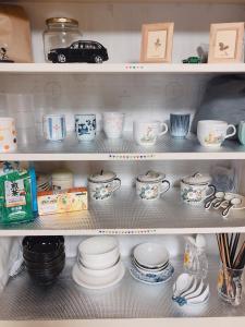 ein Regal mit Geschirr und Tassen und einem Auto in der Unterkunft Guest House Ringo in Otaru
