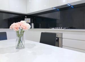 a vase of pink flowers sitting on a table in a kitchen at Pride Bentleigh Apartment with Private Garden in Melbourne