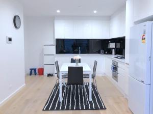 メルボルンにあるPride Bentleigh Apartment with Private Gardenの白いキッチン(テーブル、椅子付) +23枚の写真