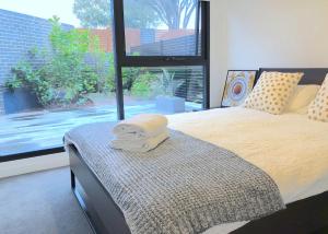 a bedroom with a bed and a large window at Pride Bentleigh Apartment with Private Garden in Melbourne