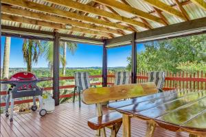 a screened in porch with a grill and a table and chairs at Byron Hinterland Villas in Clunes