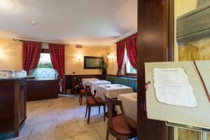 a dining room with tables and chairs and red curtains at Albergo Da Nando in Mortegliano