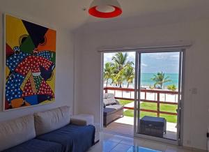 a living room with a couch and a view of the ocean at Manga Verde Beach Residence in Itamaracá
