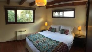 a bedroom with a large white bed with two windows at Abedul Apartamentos in San Martín de los Andes
