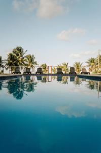 uma grande piscina com palmeiras ao fundo em Manga Verde Beach Residence em Itamaracá