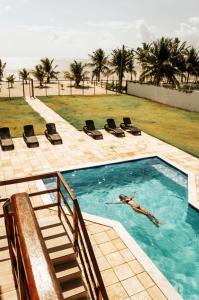 a person swimming in a swimming pool in a swimming pool at Manga Verde Beach Residence in Itamaracá