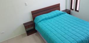 a bed with a blue comforter in a room at Mini Loft in Iquique