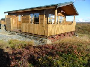 eine Holzhütte auf einem Feld mit einem Zaun in der Unterkunft Ekra Cottages in Lagarfljótsvirkjun