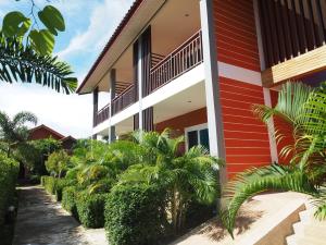 un edificio rojo y blanco con plantas a su lado en Hatzanda Lanta Resort - SHA Extra Plus, en Ko Lanta