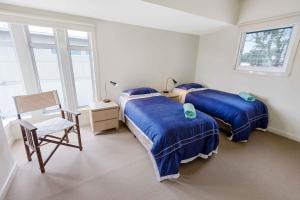 a bedroom with two beds and a chair and windows at Beach 2 in Paynesville