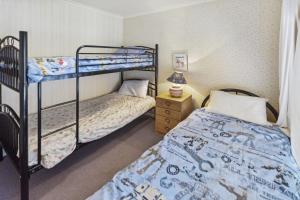 a bedroom with two bunk beds and a night stand at Cedar Cottage in Raymond Island