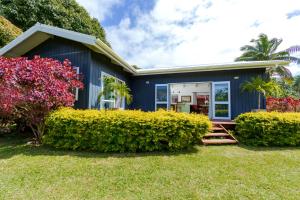 a blue house with bushes in front of it at Maine Villa in Rarotonga
