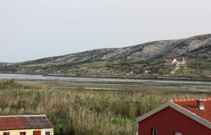 uma casa vermelha com uma montanha ao fundo em Batkoski Apartments em Pag