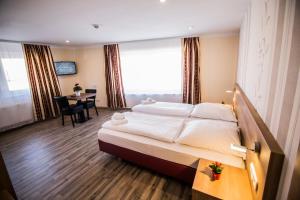 a hotel room with a large bed and a desk at Hotel Heisede in Sarstedt