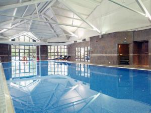 a large swimming pool in a building at Macdonald Frimley Hall Hotel & Spa in Camberley