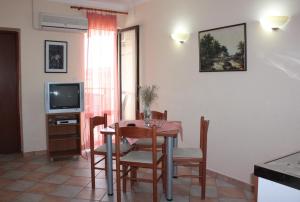 a dining room with a table and chairs and a television at Budget Apartments Batkoski Pag in Pag