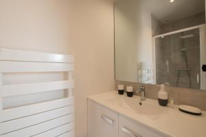 a white bathroom with a sink and a mirror at La Belle Terrasse avec climatisation et parking privé in Sarlat-la-Canéda