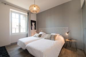 two beds in a white bedroom with a window at La Belle Terrasse avec climatisation et parking privé in Sarlat-la-Canéda