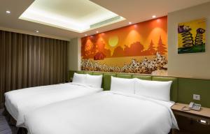 two beds in a hotel room with a painting on the wall at Shichi Hotel in Kaohsiung