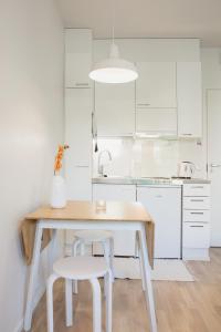 a white kitchen with a wooden table and two stools at First aparthotel Blitzen in Rovaniemi