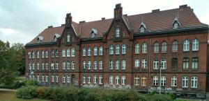 a large red brick building with a brown roof at Rooms Close To Everywhere in Gdańsk