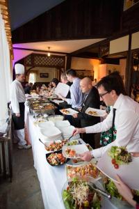 a group of people standing around a buffet line with plates of food at Kaštieľ AGATKA in Chorvátský Grob