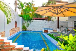 a swimming pool with an umbrella and some chairs and a table at Grande Adam Private Pool Villa in Pattaya Central