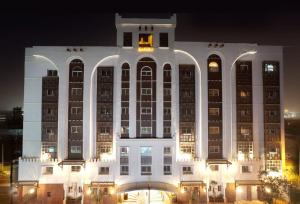 un gran edificio blanco por la noche con luces en Al Liwan Suites, en Doha