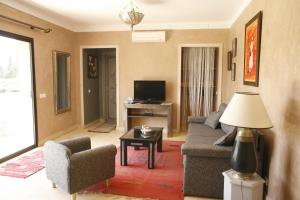 un salon avec un canapé, des chaises et une télévision dans l'établissement Oasis Jena Marrakech, à Marrakech