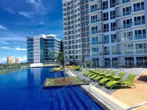 a swimming pool with lounge chairs and a building at Mactan Newtown Affordable Suite with FREE Pool & Beach in Mactan