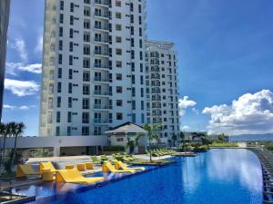 a hotel swimming pool with yellow chairs and a large building at Mactan Newtown Cebu Affordable Suite! in Mactan