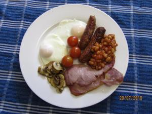 a plate of food with eggs sausage beans and tomatoes at Heather Glen Guest House in Elgin