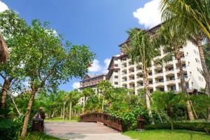 三亚Stony Brook Villa Jianguo Resort Sanya的一座白色的大建筑,前面有棕榈树