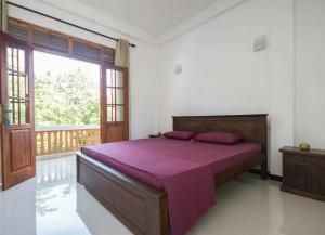 a bedroom with a bed with purple sheets and a window at Sounds of Nature mini hotel in Mirissa