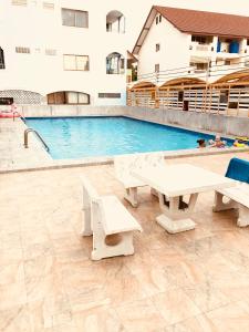 a pool with two picnic tables in front of a building at New Apartment Nearby Beach in Hua Hin
