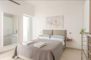 1 dormitorio blanco con 1 cama con 2 toallas en Lea's House independent solution, en Nápoles
