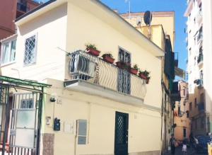 un edificio blanco con un balcón con plantas. en Lea's House independent solution, en Nápoles