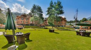 a park with chairs and an umbrella and a building at Royal Grandiose Pahalgam in Pahalgām