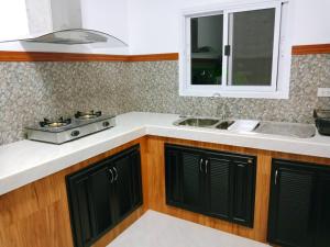 eine Küche mit schwarzen Schränken und einer Spüle in der Unterkunft Sunbeam Cottage in Ko Chang + 37 Fotos