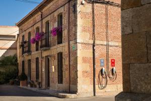 un edificio de ladrillo con flores púrpuras a un lado en Posada Real del Buen Camino, en Villanueva de Campeán