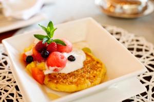 a white plate with a pastry with fruit on it at Dusk to Dawn Guesthouse in Piet Retief