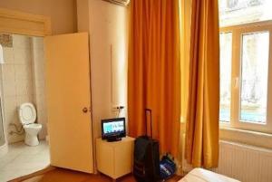 a bathroom with a toilet and a television in a room at Budak Residence in Istanbul