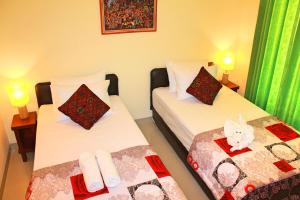 2 łóżka pojedyncze w pokoju z zielonymi zasłonami w obiekcie Werkudara Guest House w mieście Ubud