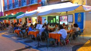 Un grupo de personas sentadas en mesas afuera de un restaurante. en TEJO HOUSE RIVER Lisbon (Cacilhas), en Almada