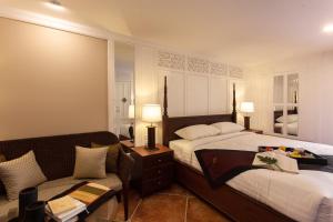 une chambre d'hôtel avec deux lits et un canapé dans l'établissement Viangbua Mansion, à Chiang Mai